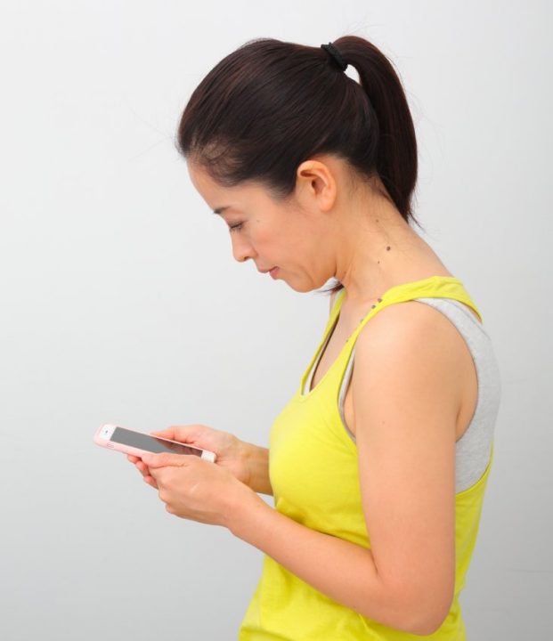 両手に持ってスマホを見ている女性