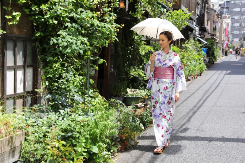 浴衣を着た女性が日傘を差して歩いている