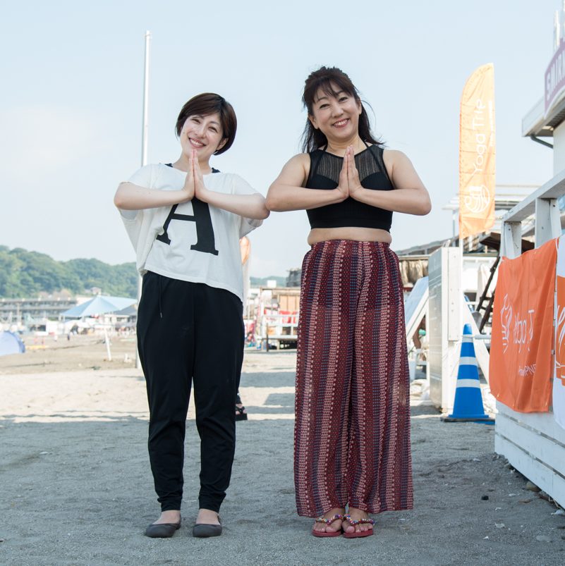 ビーチでヨガのポーズをする田邉晃子さん、山口優香子さんの全身