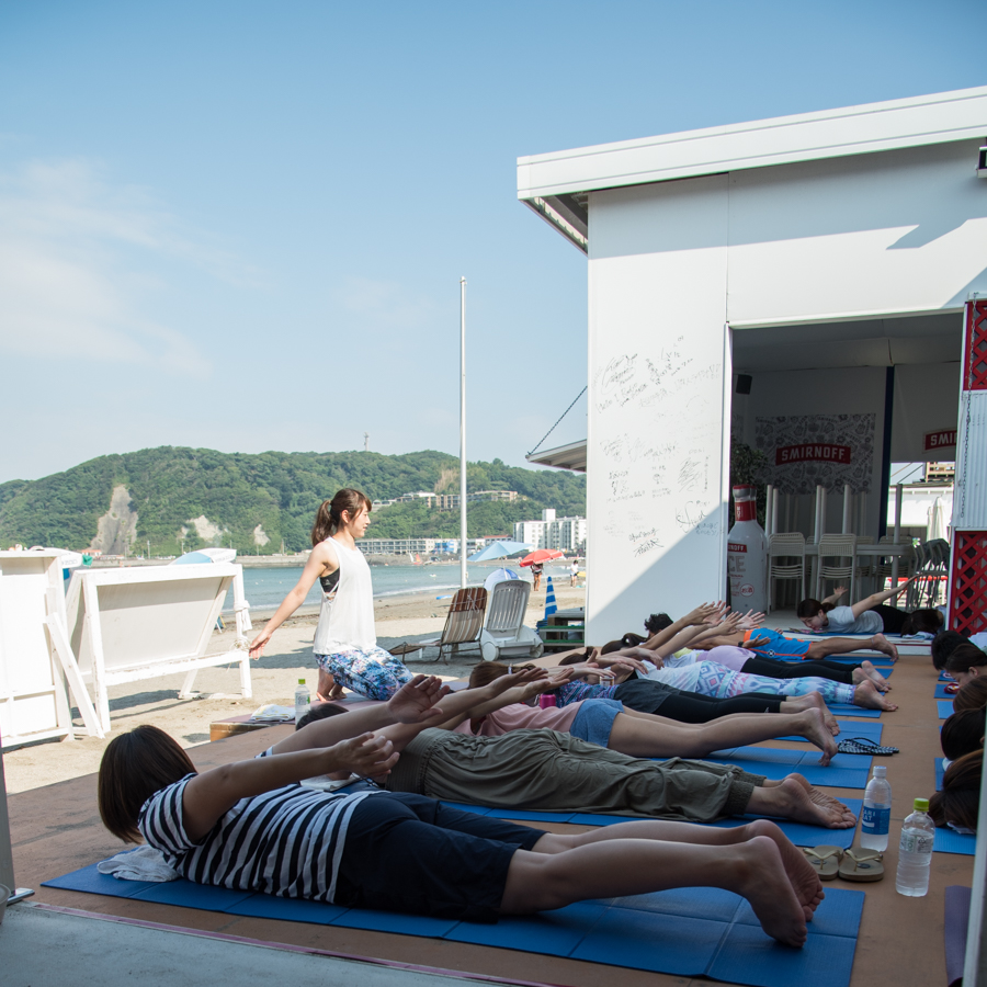 『Yoga Trip -Beach session-』でうつぶせの状態でヨガを行うインストラクターと生徒たち