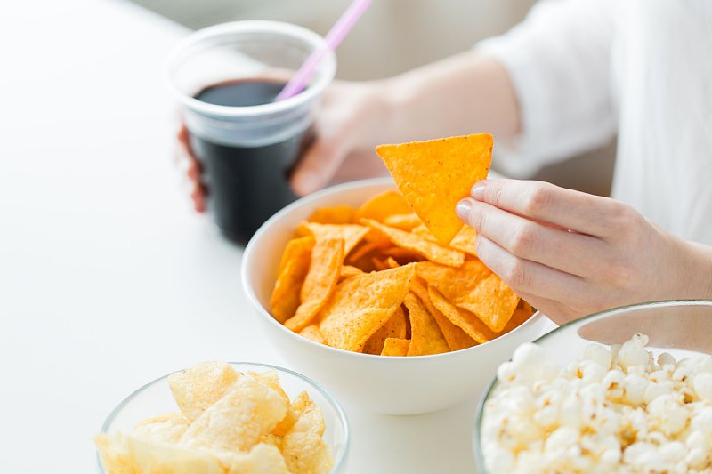 スナック菓子を食べる人。右手にはアイスコーヒー