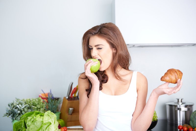 パンを片手にフルーツを食べる女性