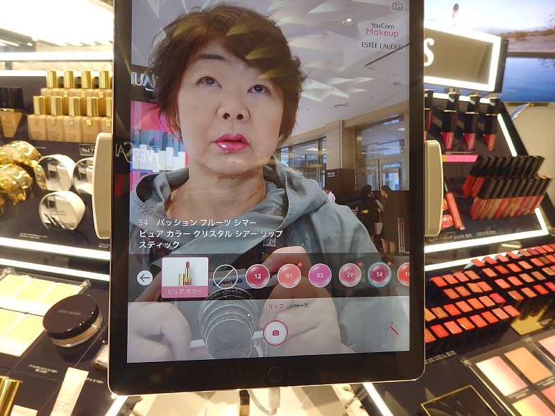 タブレットに表示されたオバ記者の顔。口紅の色を一瞬で変えることができる