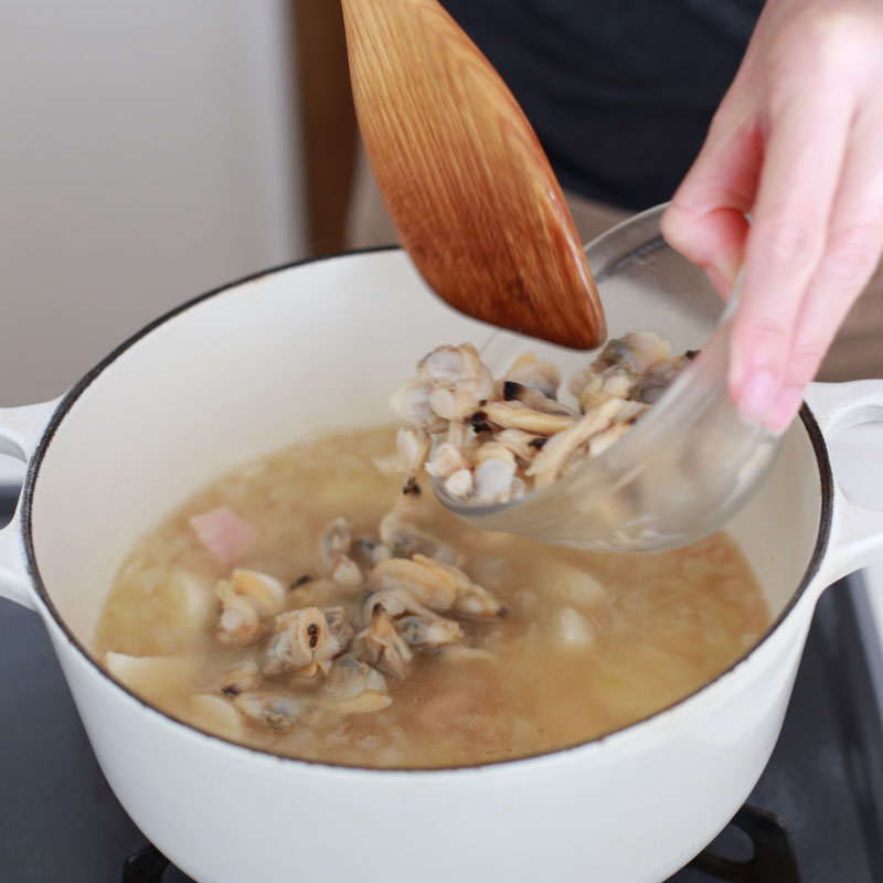 煮立った鍋に白いミネストローネの材料を入れている