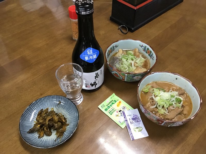 『かまたや』の牛すじの煮込み、もつ煮込み、日本酒が並べられている