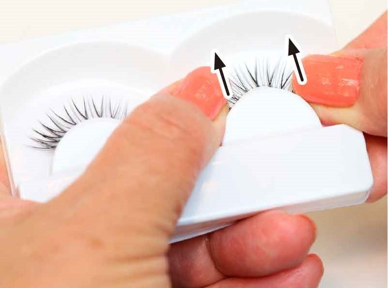両手の親指の腹を使ってつけまつげを取り出している