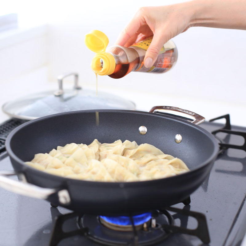 ヘルシー納豆餃子にごま油をかけている