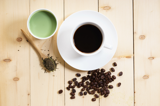 コーヒー豆とホットコーヒー、緑茶とお茶の葉がテーブルにのっている