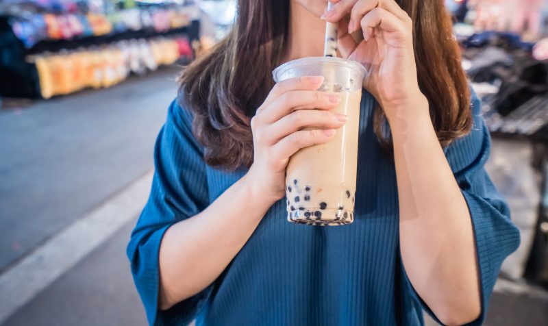 タピオカミルクティーを飲みながら街角を歩いている女性