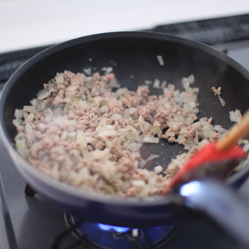 豚肉と玉ねぎをフライパンで炒めている