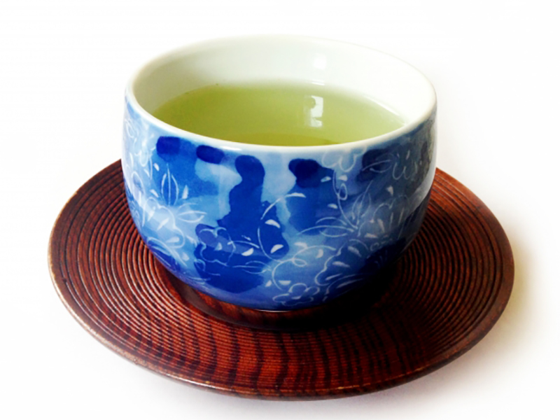 茶托に乗せた緑茶の入った湯飲み写真