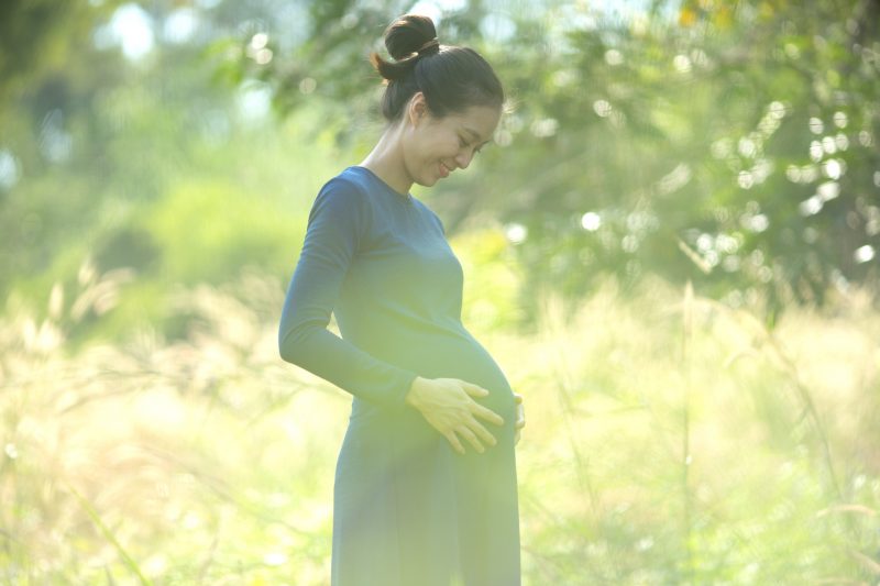 妊娠中の女性が笑顔でお腹をさすっている