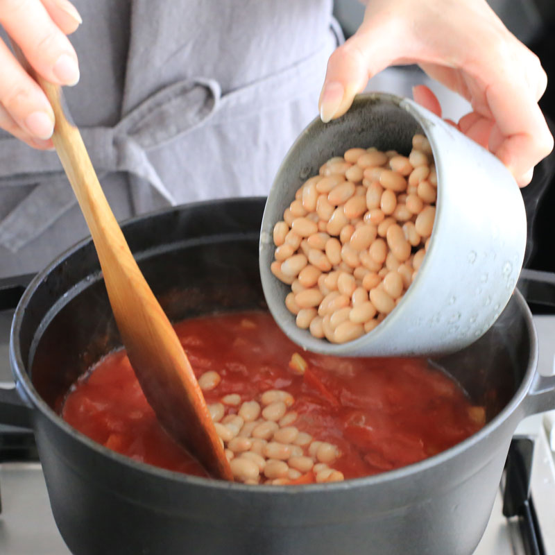 白いんげん豆を煮込んだ鍋に入れている