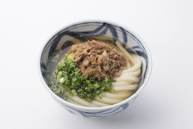 うどんに豚肉とネギがたくさんのっている