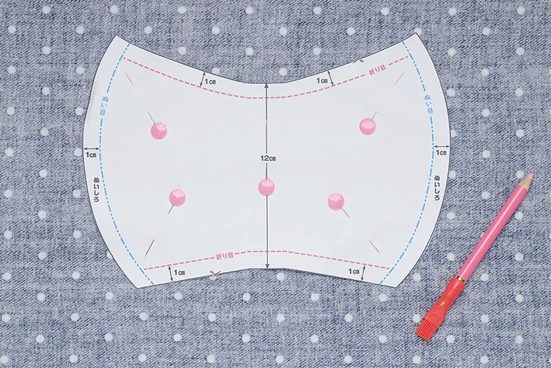 生地にマスクの型紙を置いてまち針で固定した画像