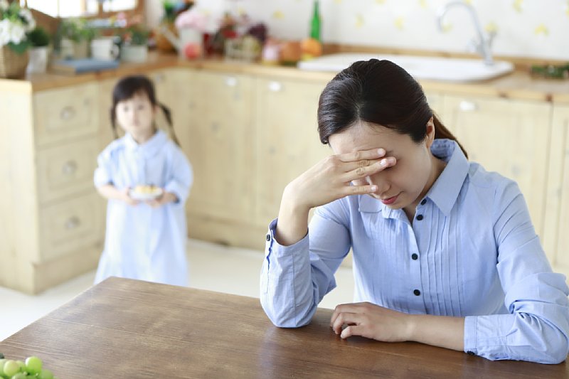 悩んでいる女性と。その後ろに女の子