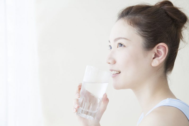 水の入ったグラスを片手に微笑む女性