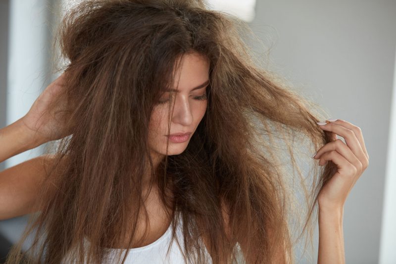 傷んだロングヘアを触る女性