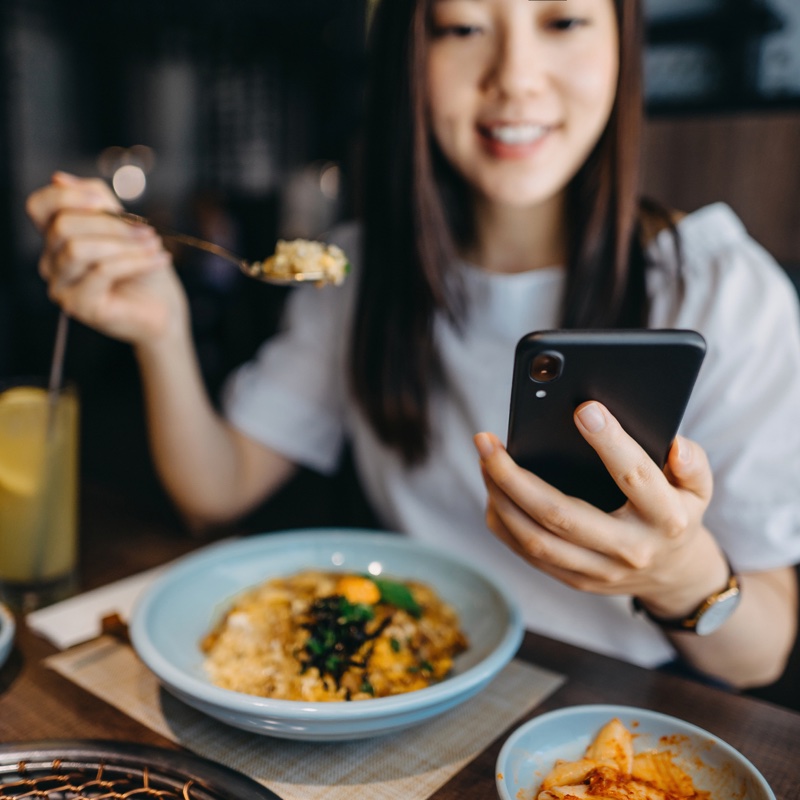 スマホを見ながら食事する女性