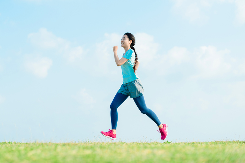 笑顔で飛び跳ねるようにランニングする女性