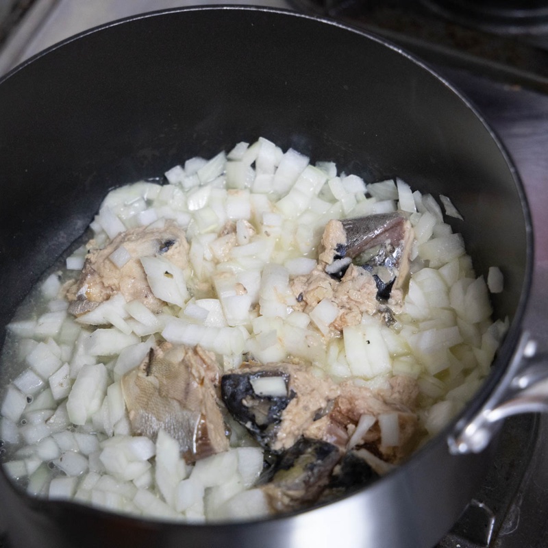 鍋でみじん切りの玉ねぎとサバ缶を煮ている