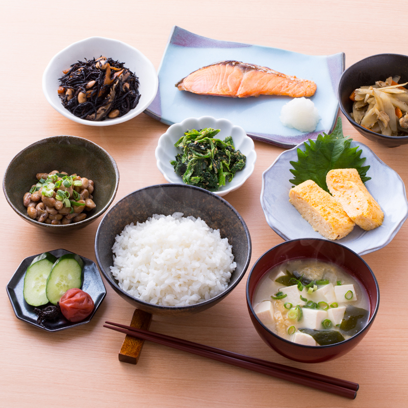 ごはんやみそ汁、焼き魚などの和食がテーブルに並んでいる