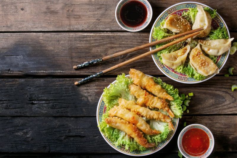 大きい皿にエビフライや餃子などが盛り付けられている