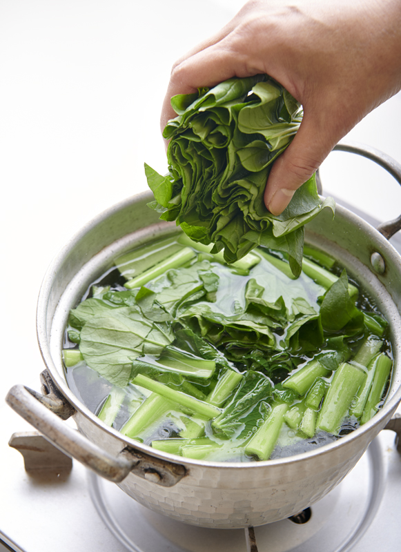 鍋に青菜を入れている