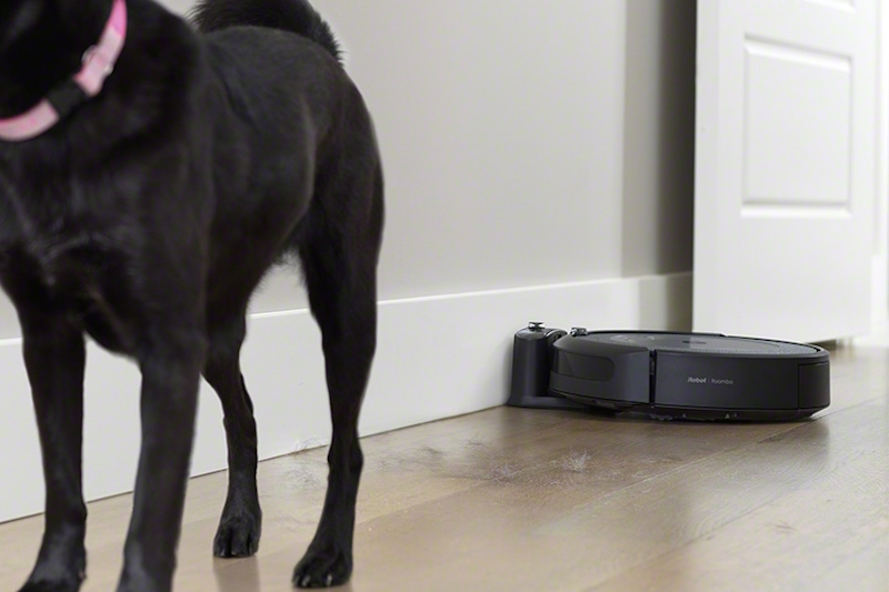 犬の後ろの床に落ちた犬の毛をアイロボット『ルンバi3＋』が取ろうとしている様子