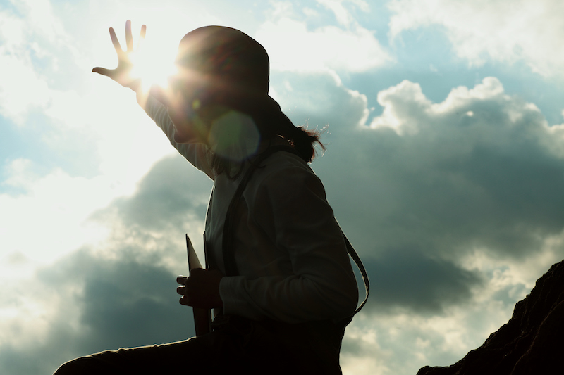 太陽に手をかざす女性