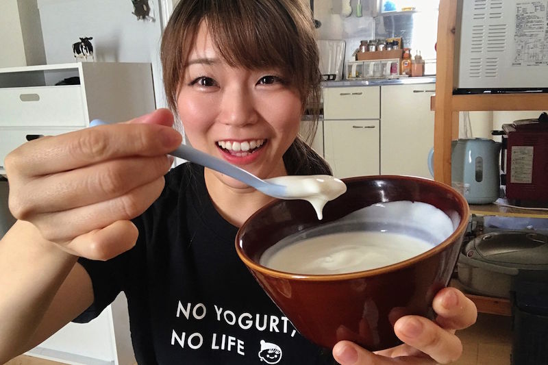 ヨーグルトマニアの向井さんがヨーグルトの入った器を左手で持ち、右手に持ったスプーンでヨーグルトをすくっている