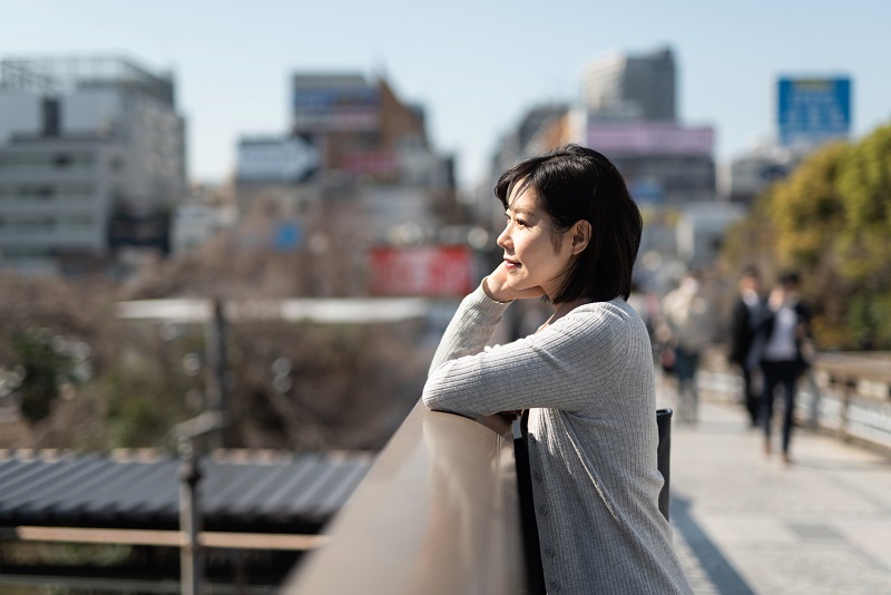 歩道橋で外を眺める女性