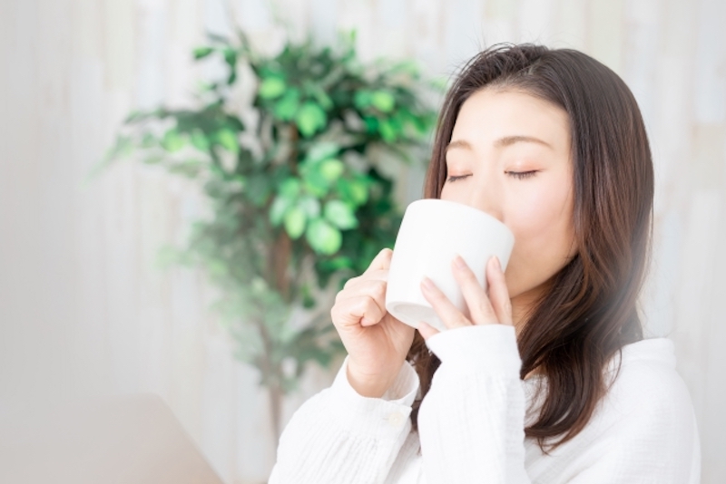 マグカップで飲み物を飲む女性