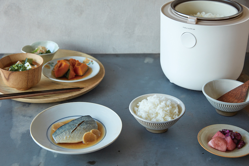 レコルトの糖質カット炊飯器の茶碗に盛られたご飯、かぼちゃの煮物、サバの味噌煮、漬物などの皿が周りに並ぶ