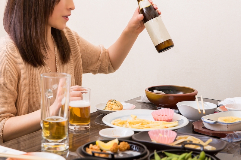 いろいろな食べ物を前にワインを手にする女性