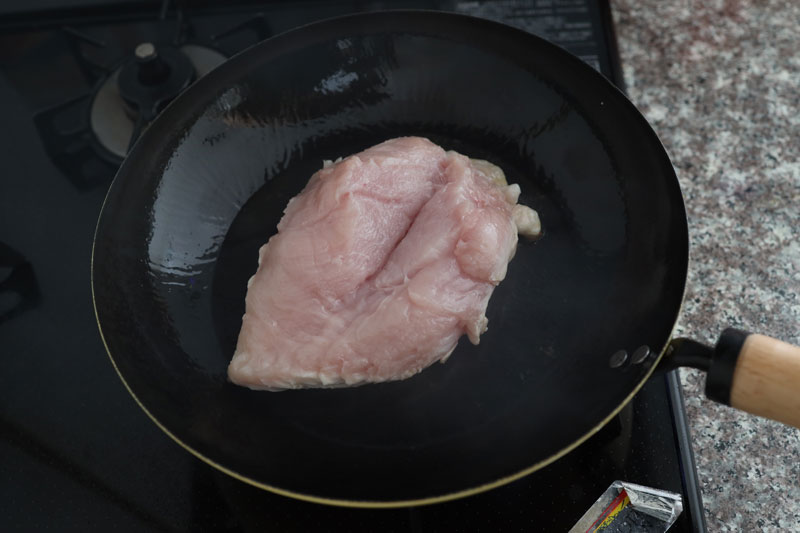 フライパンでサラダ油を中火で、熱し、鶏むね肉を皮目から焼く。焼き色がついたら、ふたをして弱火で7分蒸し焼きにする