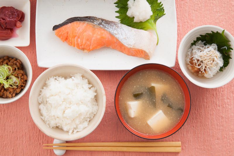 ごはんと味噌汁と鮭などが並んだ食卓