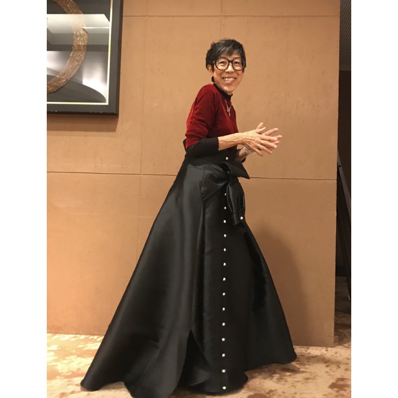 赤いトップスと黒いロングスカートを合わせたファッションの西さん