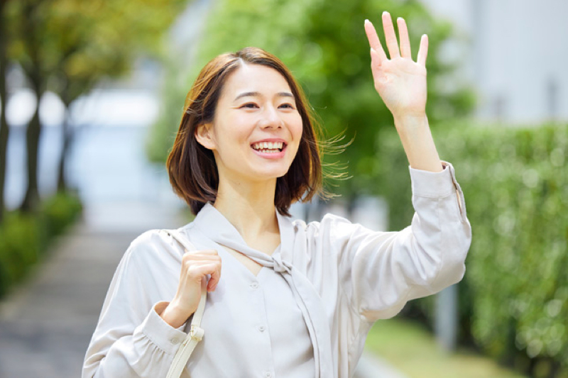 手を上げ笑顔の女性