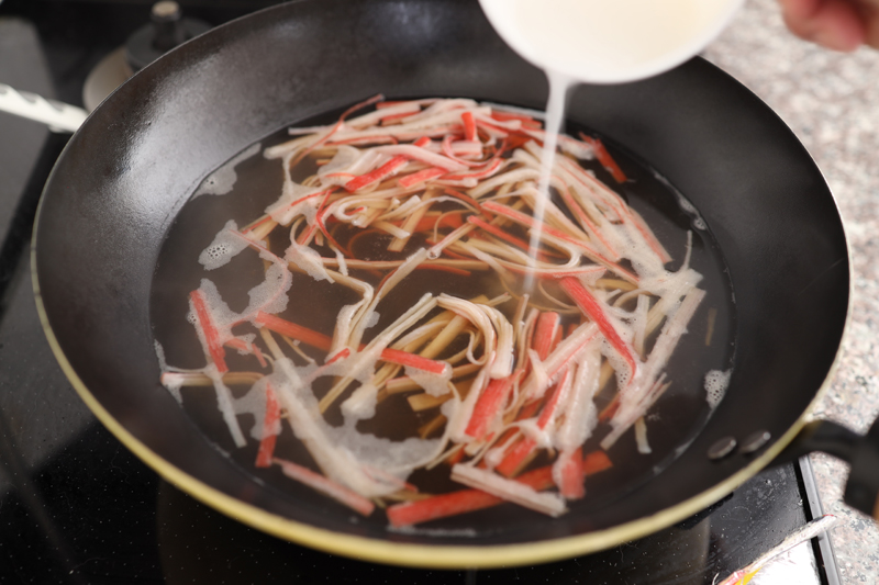 フライパンにあんかけ用カニカマ、【A】を入れて熱する。水溶き片栗粉を少しずつ入れてとろみをつける。水溶き片栗粉は片栗粉：水＝1：1で