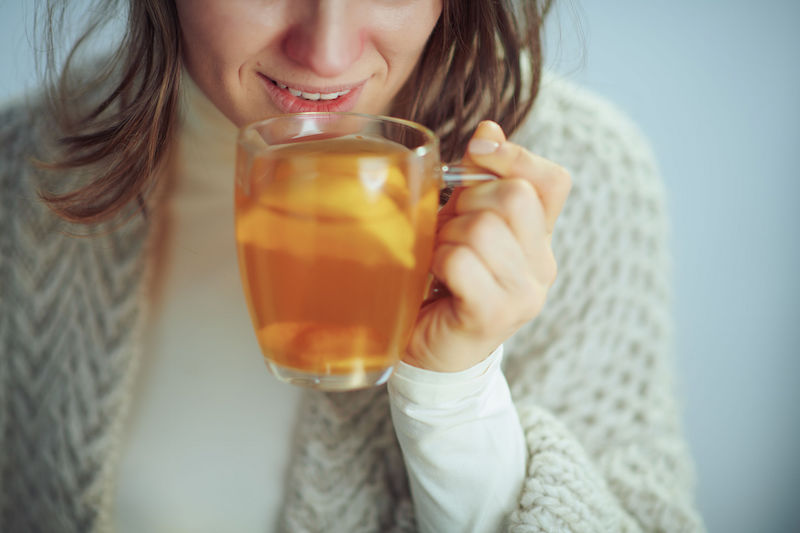 レモンの入ったホットドリンクを飲む女性の口元