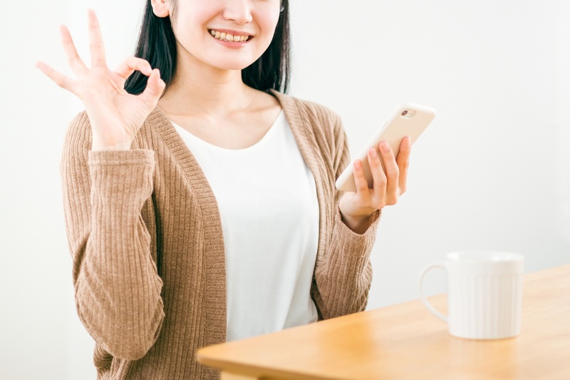 スマホを持ってOKサインを出す女性