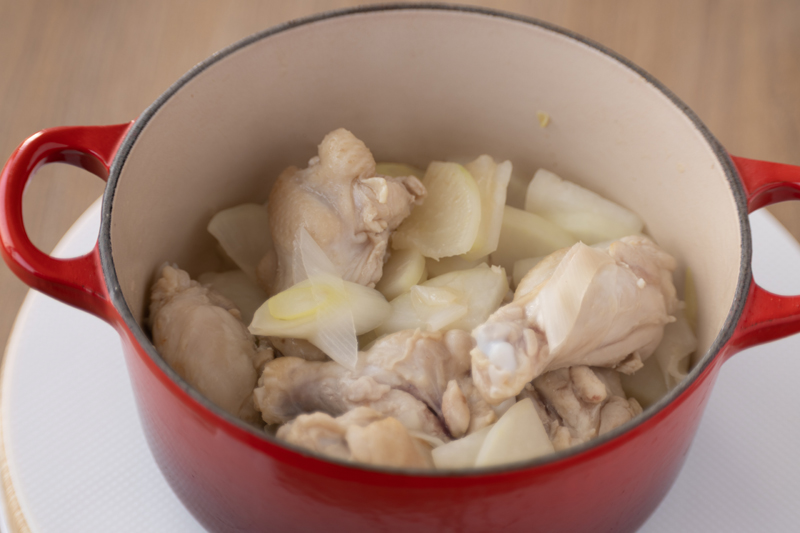 鍋でごま油を中火で熱し、手羽元、長ねぎ、大根を焼き色がつくまで焼く