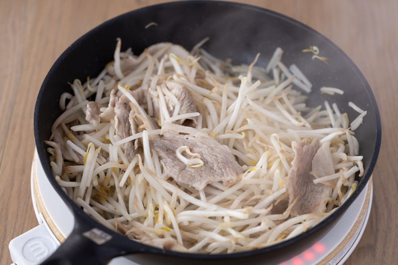 フライパンでサラダ油を中火で熱し、豚こま肉に塩・こしょうをして炒める。肉の色が変わったらもやしを加えてしんなりするまで炒める