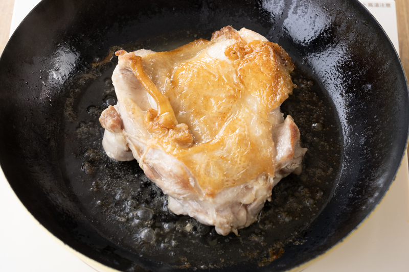 フライパンでサラダ油を中火で熱し、鶏もも肉を皮目から焼く。焼き色がついたら、ふたをして弱火で7分蒸し焼きにする。鶏もも肉を裏返し、ふたをせずに中に火が入るまで焼く。