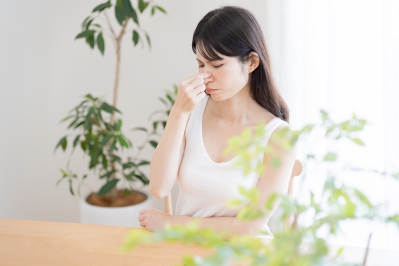 鼻を押さえる女性