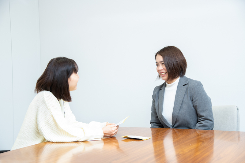 白い服の女性とジャケットを着た女性が話している