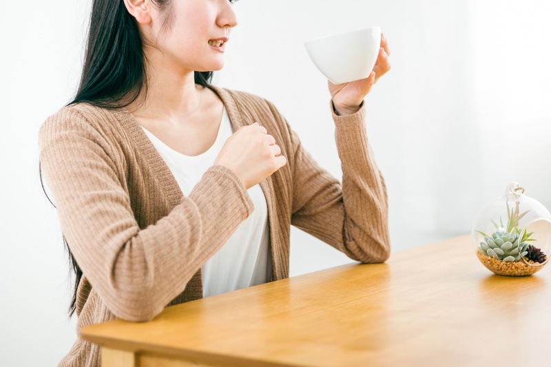 まずそうに飲み物を飲んでいる女性