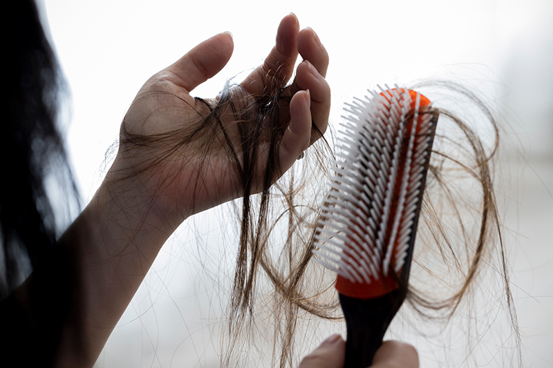 抜けた髪の毛が絡まった手のひらとヘアブラシ