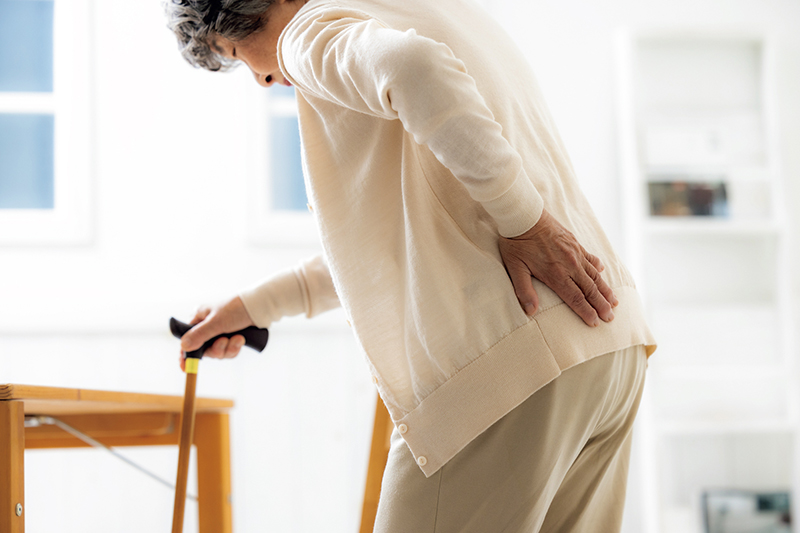 杖を持ち越しを擦る女性